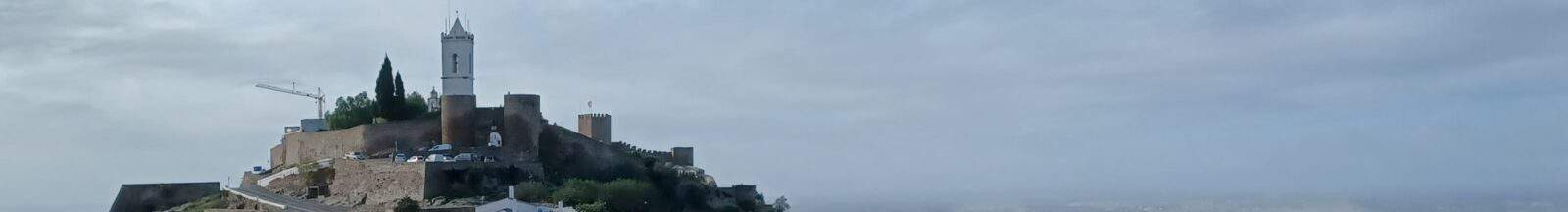 Hilltop castle with white tower.