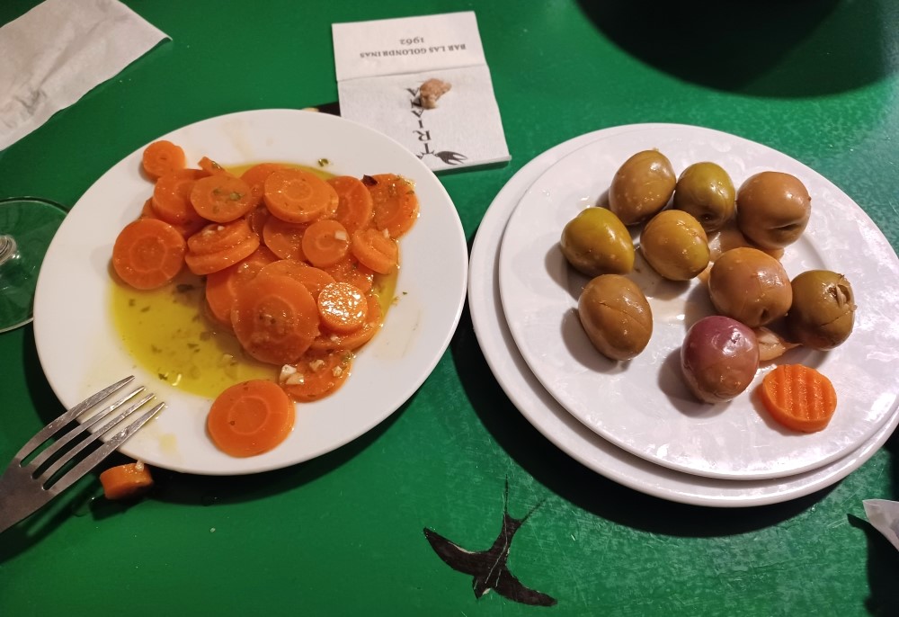 Two plates of food on a table with carrots and potatoes.