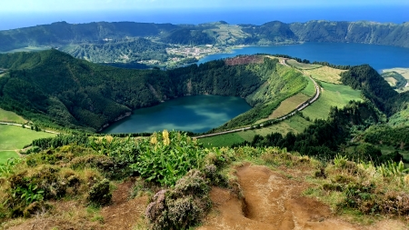 A view of the ocean from above, with a lush green hillside.