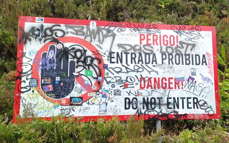 A sign with graffiti on it in the middle of nowhere.