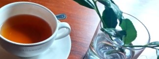 A cup of tea on the table next to a vase.